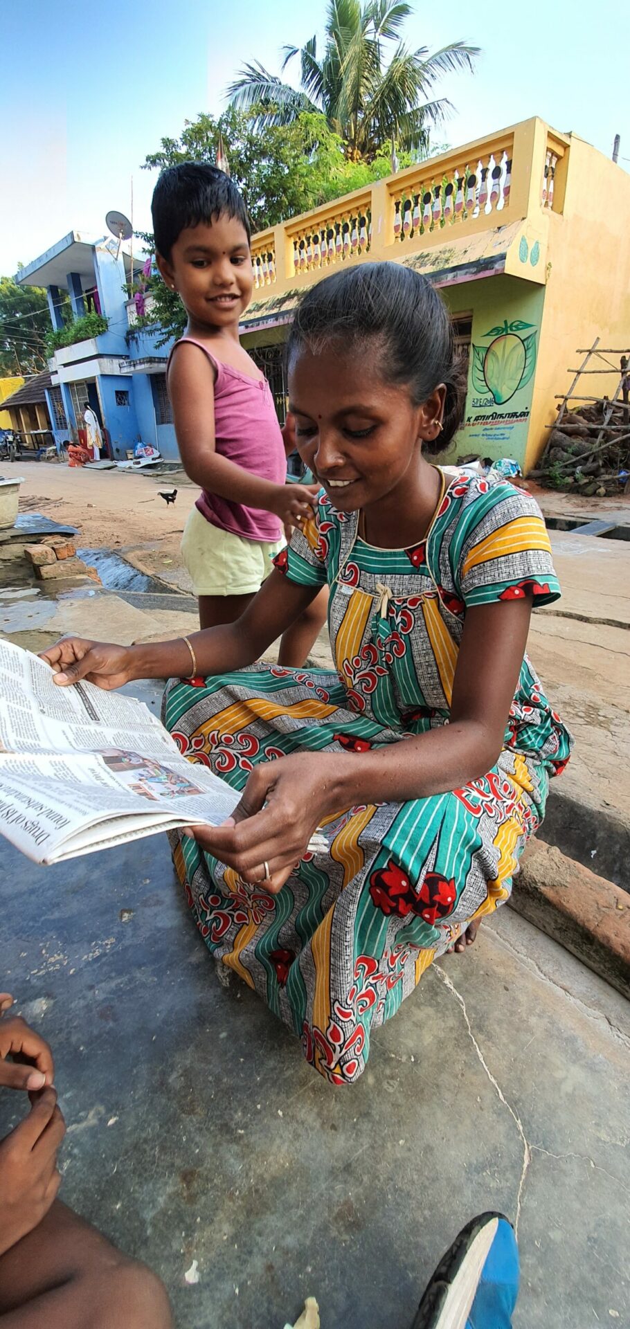 Nachbarin Divya liest einen Artikel über 'The Washing Machine Project'. Foto by 'The Washing Machine Project'.