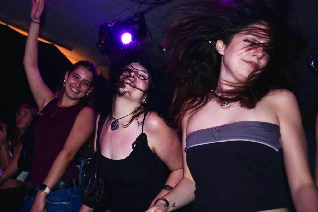 Bei Mama geht tanzen sind nur Frauen anwesend. Foto von <a href="https://unsplash.com/de/@anitamonteiro?utm_source=unsplash&utm_medium=referral&utm_content=creditCopyText">Anita Monteiro</a> auf <a href="https://unsplash.com/de/fotos/drei-frauen-die-bei-einem-konzert-mit-fliegenden-haaren-tanzen-p04koMVacI0?utm_source=unsplash&utm_medium=referral&utm_content=creditCopyText">Unsplash</a> 